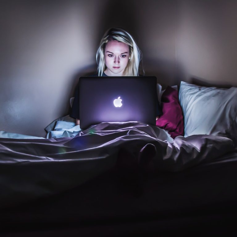 Woman Looking At Her Computer in Bed | Is Phonography Use A Fantasy Of Transcendence? | Public Square Magazine | Is Porn Fantasy? | Transcendence Porn