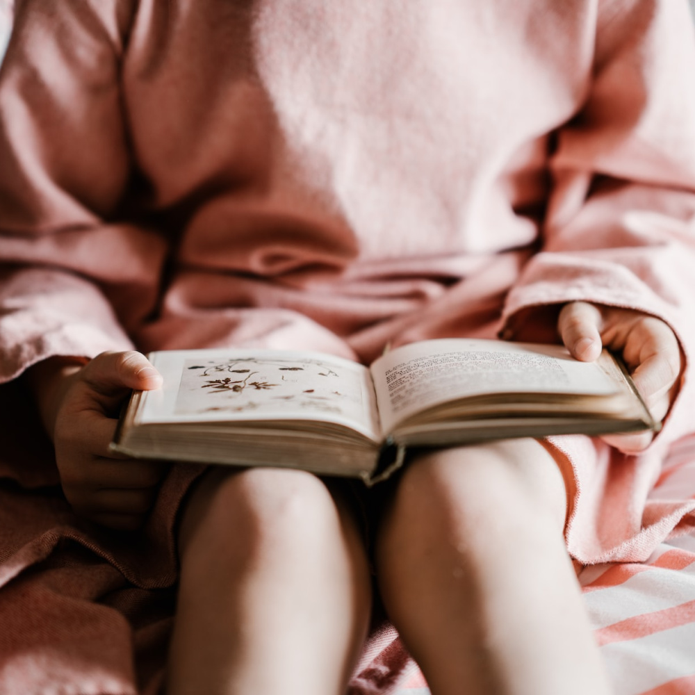 Girl in Pink Holding Book Open | Protecting Kids From Explicit Material Shouldn’t Be Controversial | Public Square Magazine | Explicit Books in Schools | Explicit Children's Books