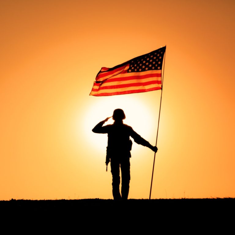 A resolute figure atop a mountain showcases a steadfast commitment and fidelity to country with a fluttering American flag.