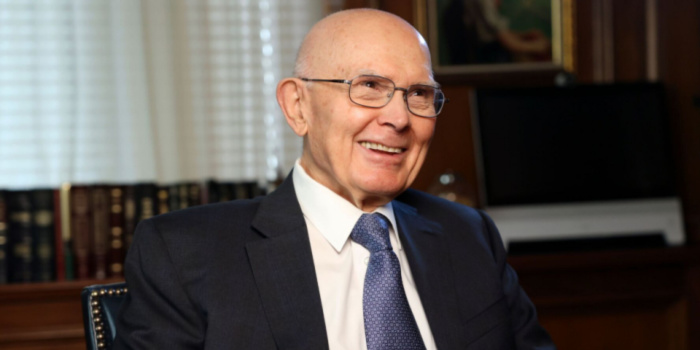 President Dallin H. Oaks seated, smiling gently, wearing a dark suit and tie in an office setting