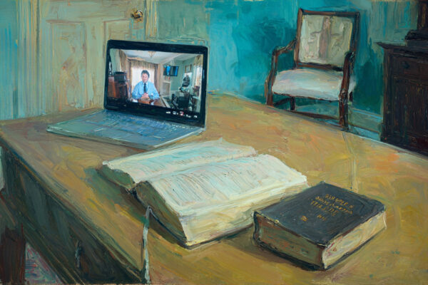 A tidy study with a closed Bible on a desk beside an open laptop showing a podcaster on a video feed, the chair slightly pulled back as if someone just stood up.
