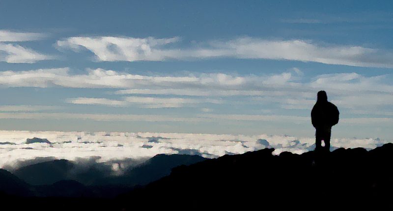 Dark heavenly clouds in the sky. Beautiful orange and blue color with the silhouette of a mountain on the bottom of the frame.