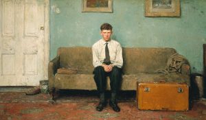 An early returned missionary sits alone in a quiet living room beside a suitcase.