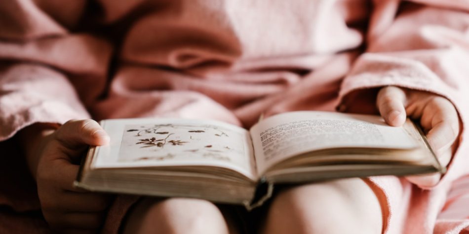 Girl in Pink Holding Book Open | Protecting Kids From Explicit Material Shouldn’t Be Controversial | Public Square Magazine | Explicit Books in Schools | Explicit Children's Books