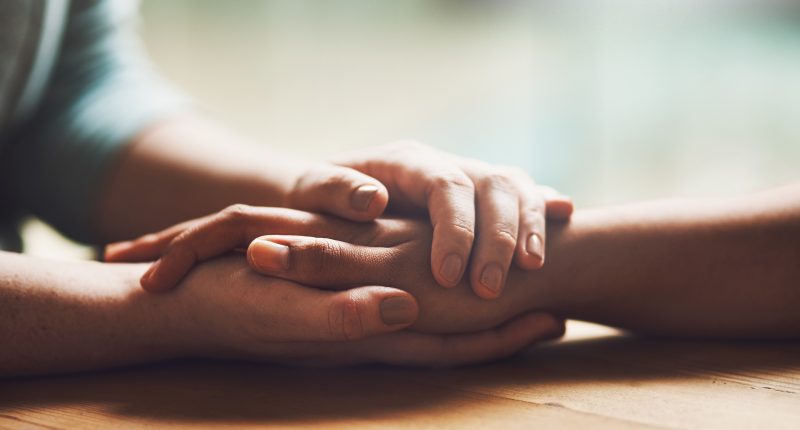 Shot of two people holding hands in comfort