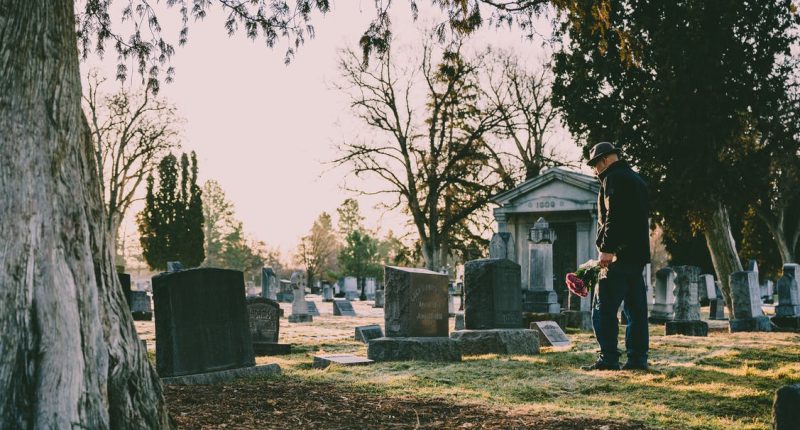Man w/ Flowers, Looking at Tombstone in Cemetery | Make The Good Times Stop: Pop Culture’s Fixation on Eternal Oblivion | Public Square Magazine | Eternal Oblivion
